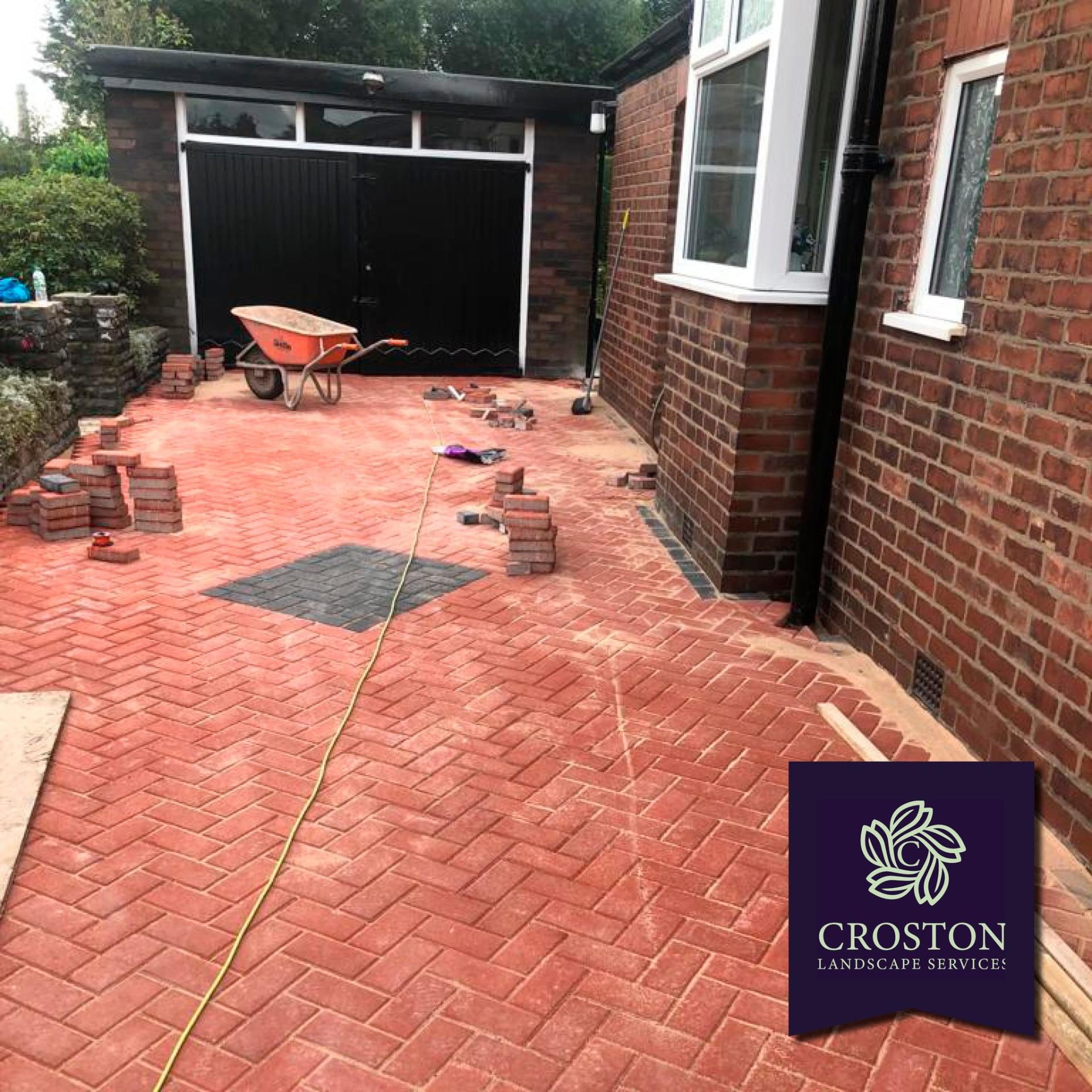 Red herringbone block-paved driveway alongside a brick bungalow
