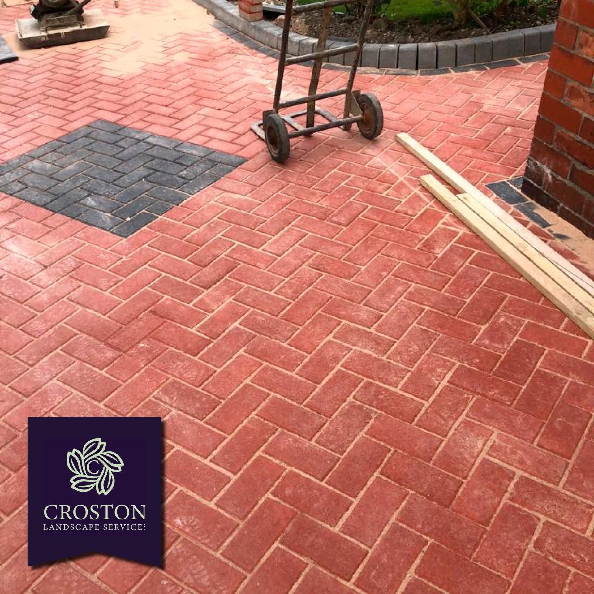 Red herringbone block paving with charcoal feature inset