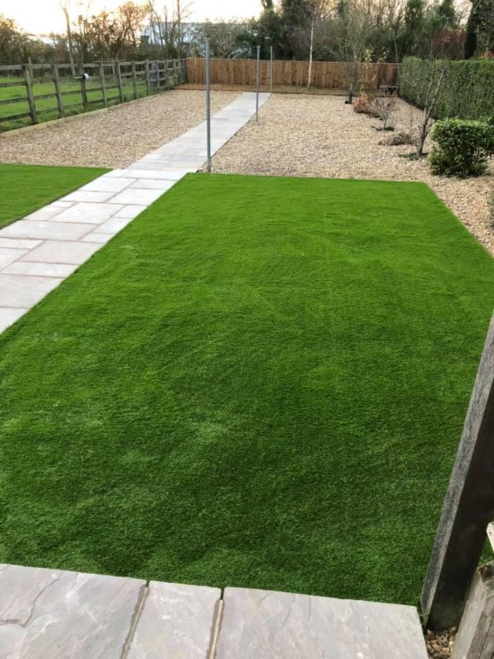 Contemporary artificial grass lawn with grey porcelain stepping stone path and gravel border